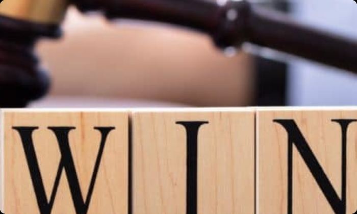 A judge's gavel behind wooden blocks spelling WIN